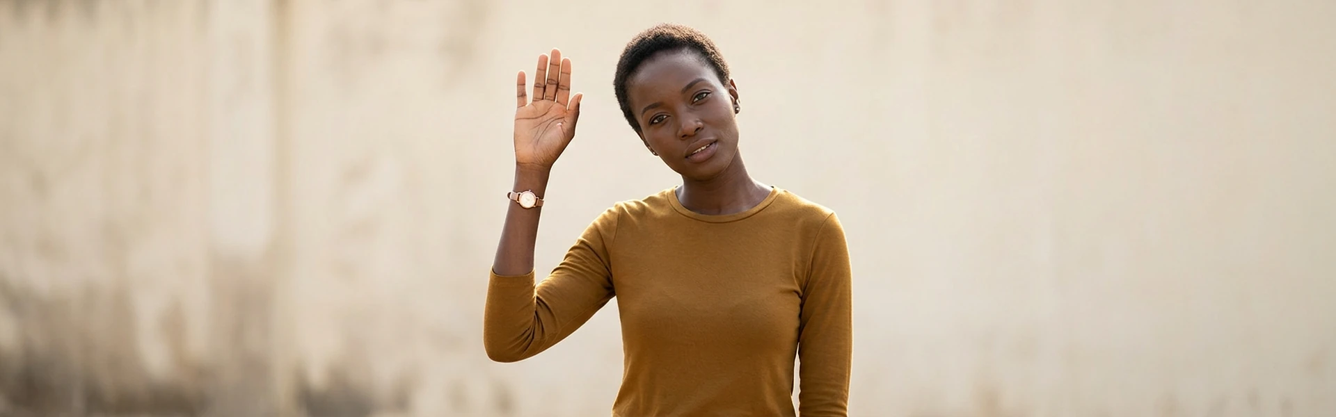A Nigerian woman stands with one hand raised and open, in the posture of asking a question
